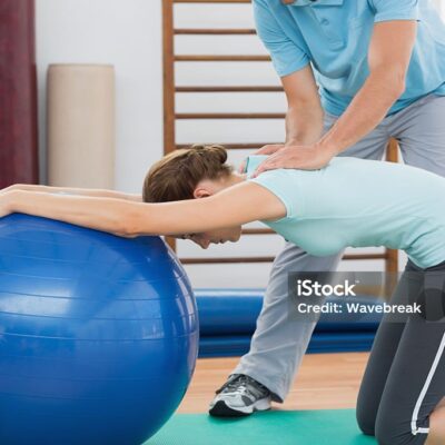 Male coach assisting woman exercising in gym